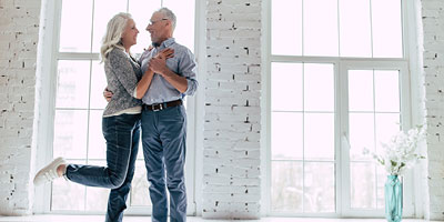 Senior adult couple dancing in their living room.