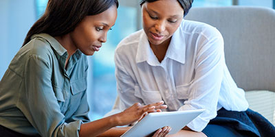 Two African-American women discussing who to name as their life insurance beneficiary. 