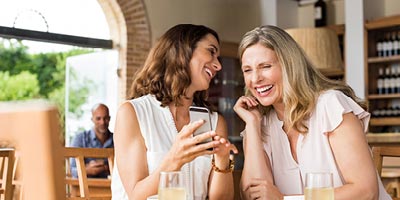 Mother and daughter laughing while looking at a phone.