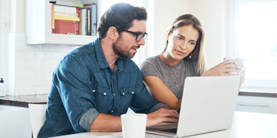 Man and his wife in their 40s, drinking coffee and talking at their kitchen counter.