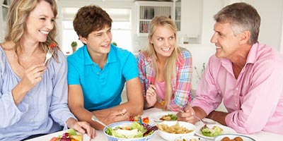 Family with grown children eating healthy lunch at their kitchen table.