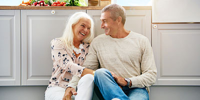Older couple laughing in kitchen.