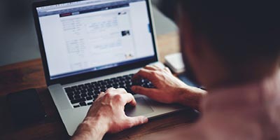 Man researching information about life insurance policies on his laptop. 