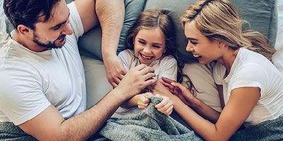 Mother, father and daughter laughing together at home.