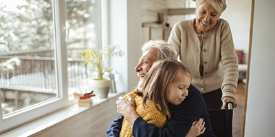 Doting grandpa hugs his granddaughter while grandma looks on