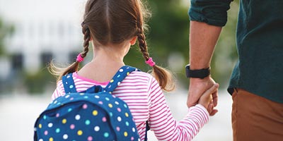 Father and daughter with backpack walking to school