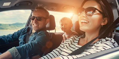 Photo of mom, dad and young son in the car, taking a road trip.