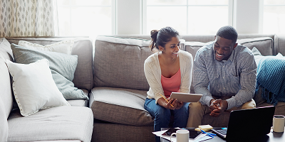 Young couple looking at paperwork and using a laptop