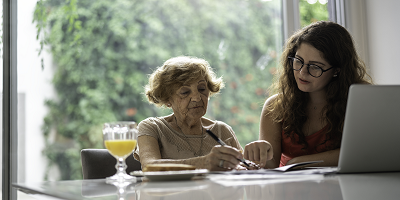 Young woman helping grandmother with laptop