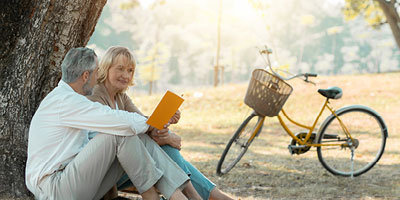 A senior adult couple resting after a bike ride and discussing their last will and testament plans.