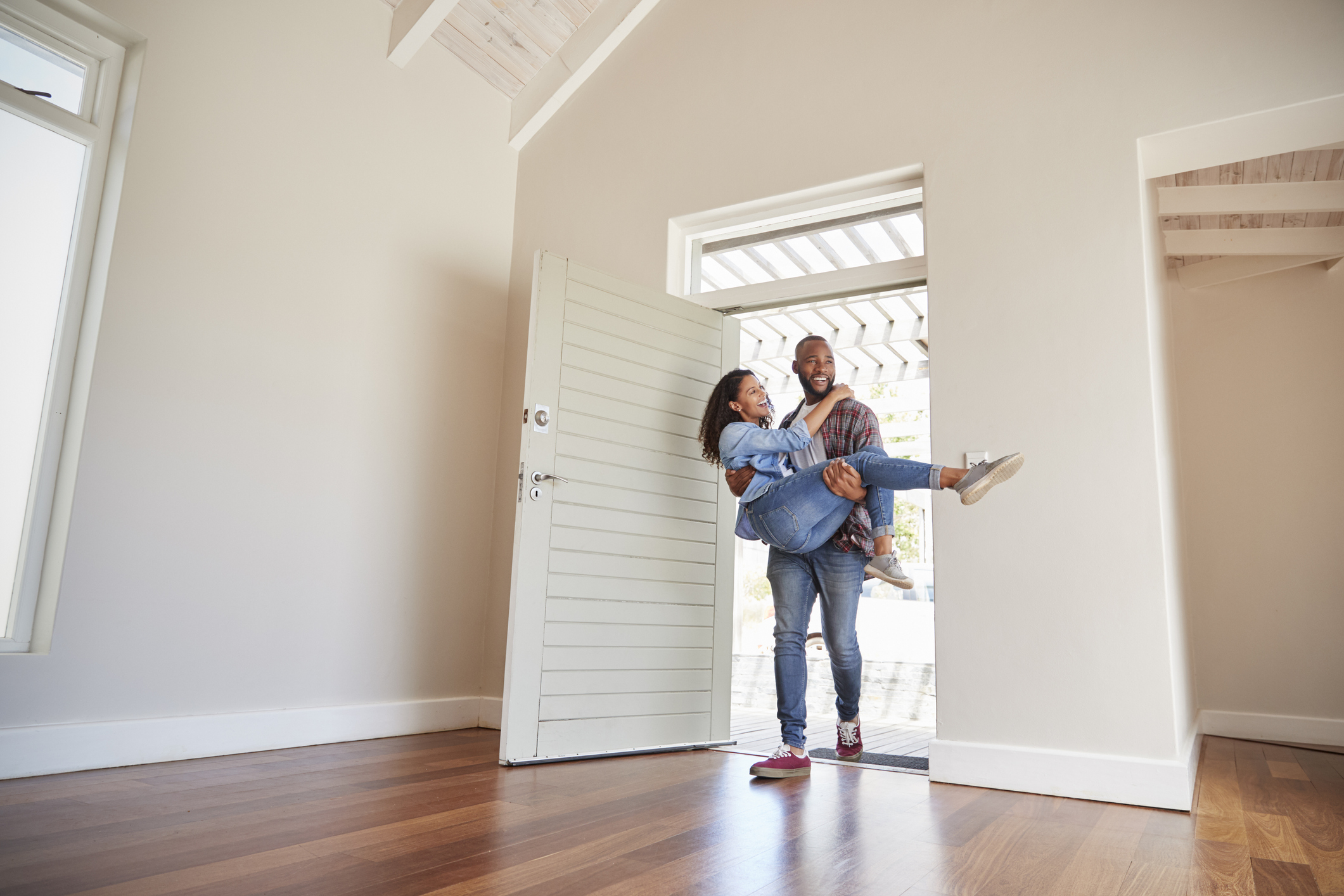 A man carries his wife over the threshold and into their new home.