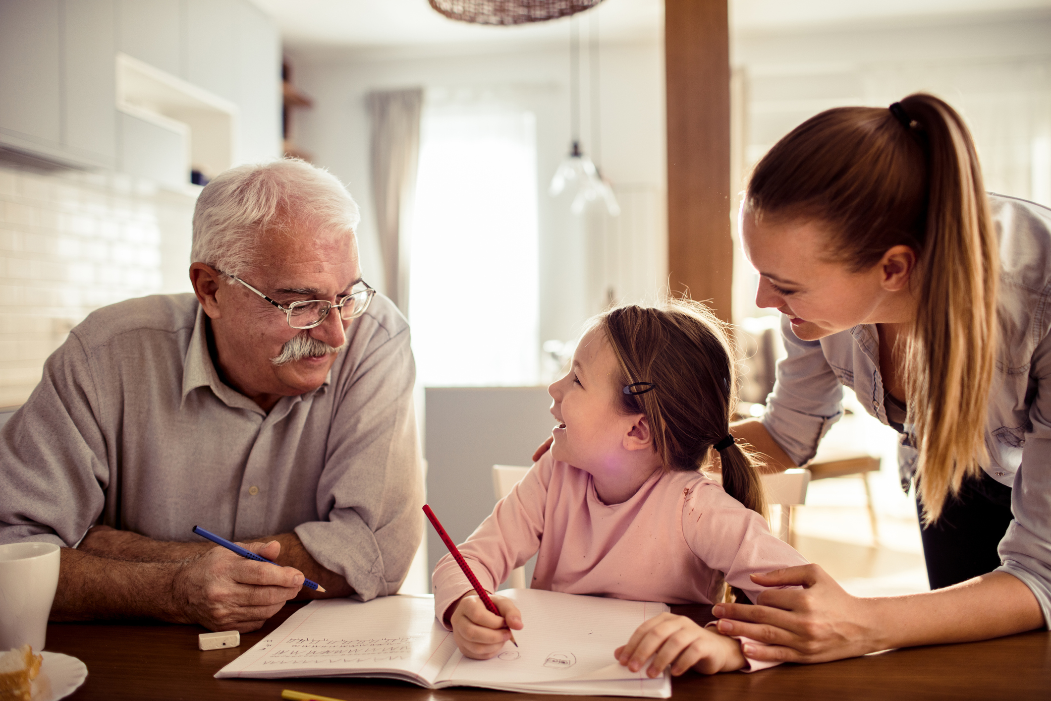 A grandfather and a mom help a little girl do homework.