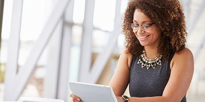 Woman in her 20s smiling and looking at an iPad.