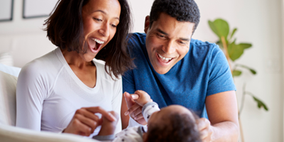 Mother and father smiling at a newborn.