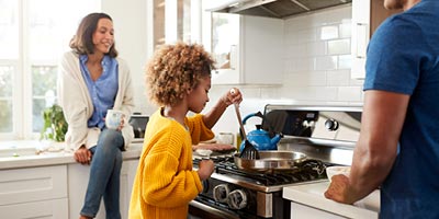 Young family at home cooking together.