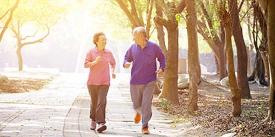 Older couple running in park; they may be candidates for life insurance that covers a funeral or burial expenses.