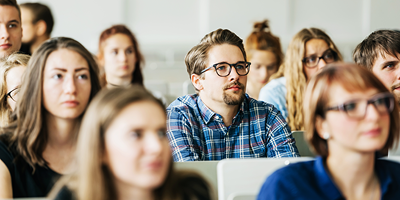 Young man sits in a college classroom.