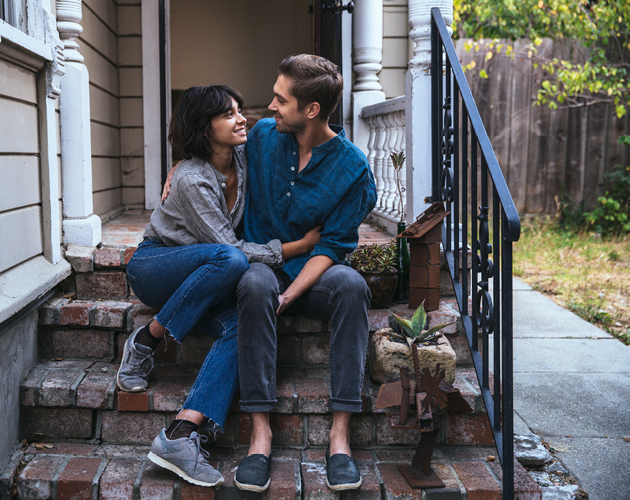 Young couple sitting on steps of first home.