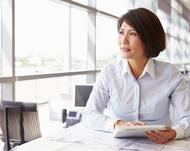 Middle-aged woman at desk with paperwork.