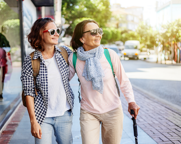 Adult woman walking down city street with her elderly mother.