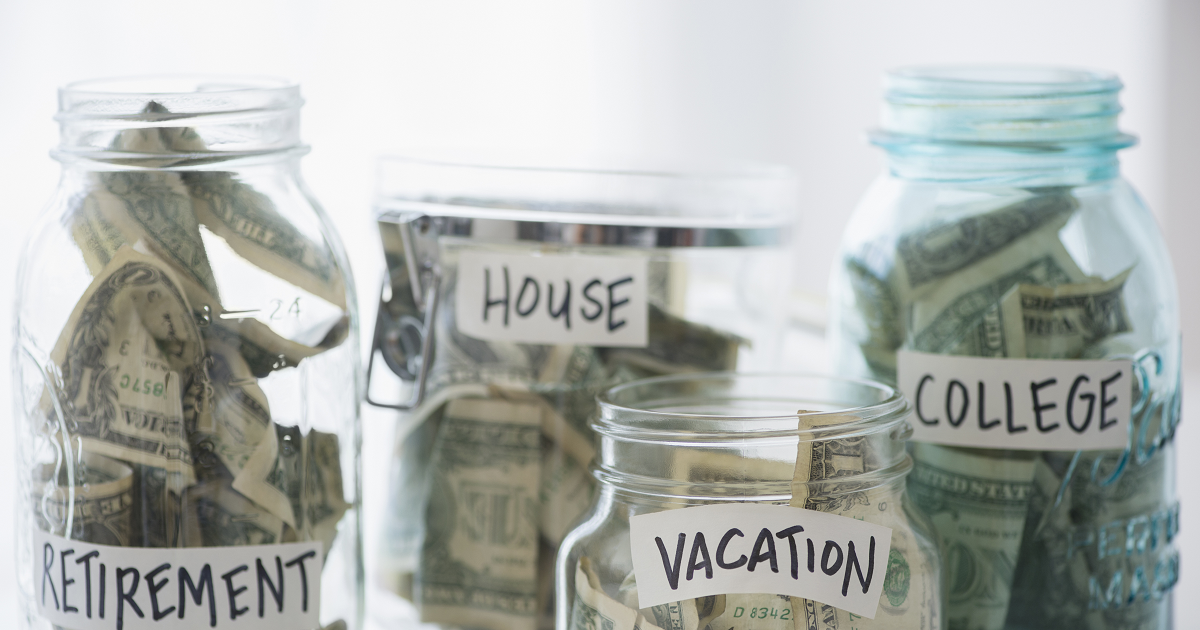 Dollar bills in glass jars labeled retirement, house, vacation and college.