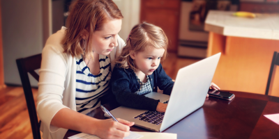 Mother sitting with her young child on her lap as they budget on the laptop.