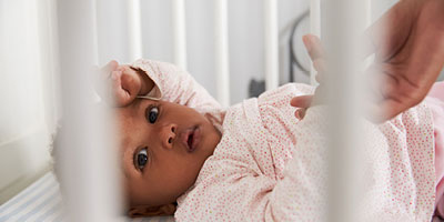A close-up of an African-American infant laying in a crib.