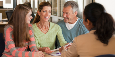 A soon-to-be college student sits and discusses college financial support options with her parents and a college admissions representative.