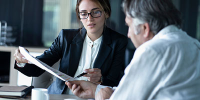 Professional woman shows an older man where to sign a document