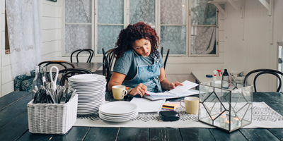 A young freelancer sitting at her desk and speaking with her clients on the phone.