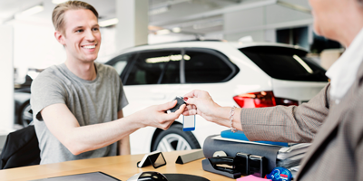 Young man taking the keys after just purchasing a car.