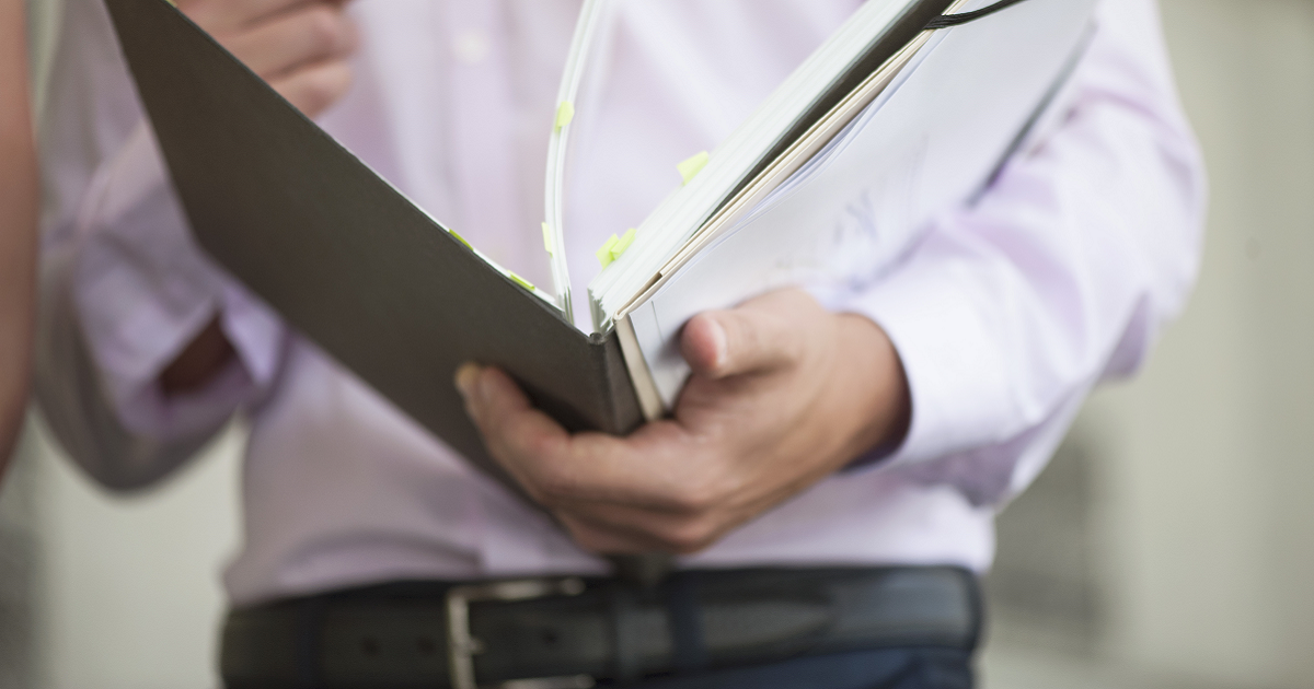 Man flipping through binder of paperwork.