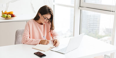 Young woman working on her budget at the kitchen table.