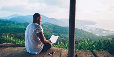 Young man sitting outside while browsing his laptop. 