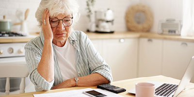 Woman rubbing forehead as she tries to find insurance policy information after the death of her loved one.