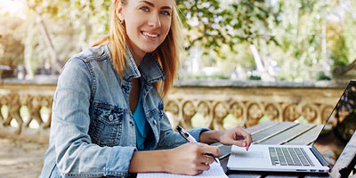 A woman smiling as she looks up from a computer while searching for information.