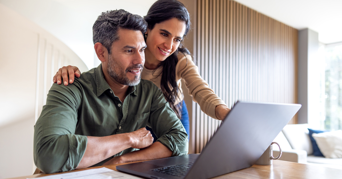 Middle aged husband and wife at home looking at their retirement strategy on computer in living room.