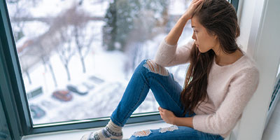 Latino woman staring out the window, looking very sad.