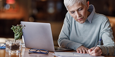 Senior woman studying her financials at a desk with laptop