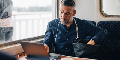 Man sitting on a train and working on his laptop.