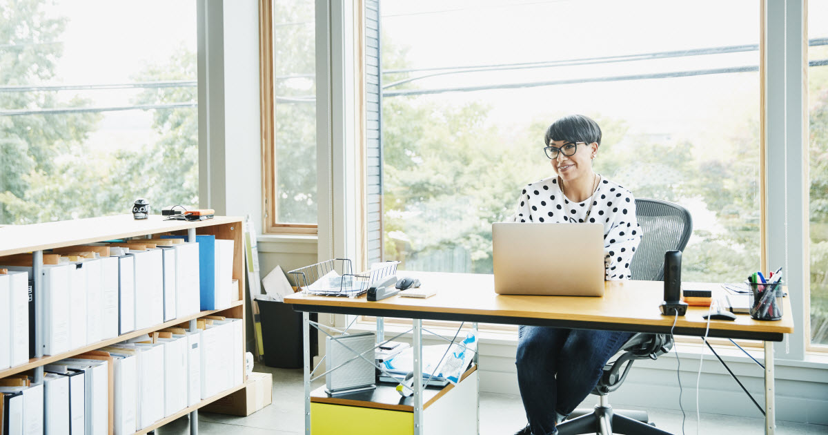 Female business owner sitting at desk in sunny office