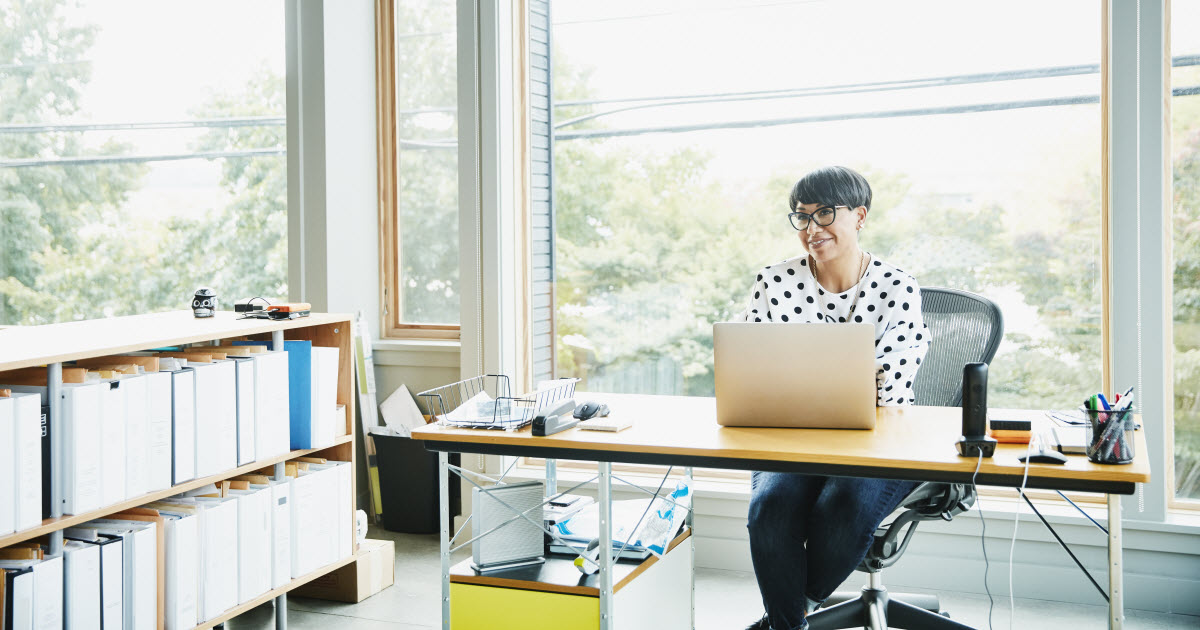 Female business owner sitting at desk in sunny office