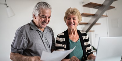 Senior couple looking at laptop and paperwork
