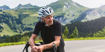 Senior man out biking along a beautiful mountainside background.