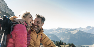 Young outdoorsy couple with a snowy mountain backdrop.