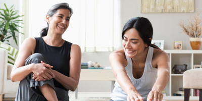 Two happy women chatting while doing a home workout.