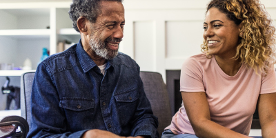 Older man and adult daughter sitting in living room and smiling.