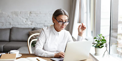 Retirement-age businesswoman uses laptop in bright and airy office