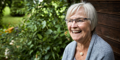 Happy-looking senior woman sitting outside, smiling.