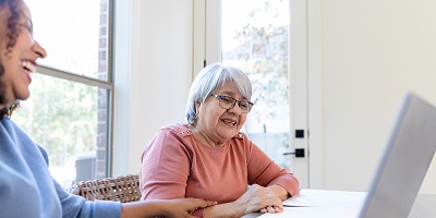 Senior woman smiling while evaluating her budget on a computer